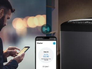 Máy giặt LG TV2519DV7B Inverter 19 kg 6 Hình ảnh bên trái cho thấy một người đàn ông đang nhìn xuống điện thoại của mình.  Hình bên phải cho thấy một chiếc máy giặt gia đình.  có đèn xanh trên màn hình  Ở trung tâm của cả hai hình ảnh là ảnh chụp màn hình điện thoại hiển thị máy giặt trên ứng dụng LG ThinQ và biểu tượng kết nối.